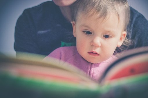 Best Books for One Year Olds - toddler being read to by an adult. 